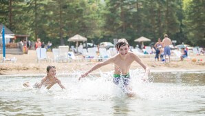 Escena de playa con gente nadando y jugando en el agua.
