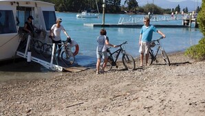 A boat docked at a pier with people and bicycles nearby. - Mapua Studio  High Quality Accommodation  (Mapua (Ruby Bay))