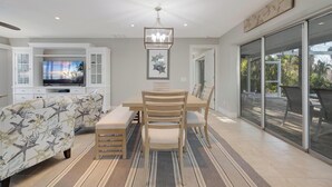 Un soggiorno moderno con zona pranzo, un divano con motivo naturale, un lampadario e un'ampia finestra vista.