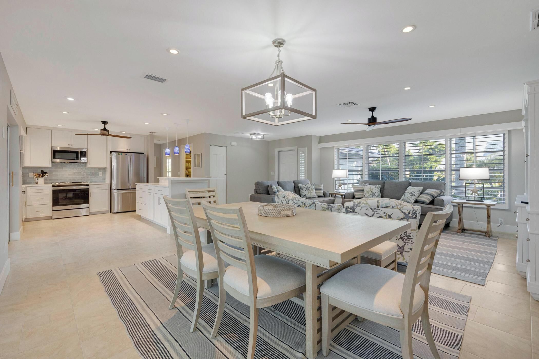 A modern kitchen with stainless steel appliances, a dining area with a large table and chairs, and a cozy seating area with a sofa and a coffee table.
