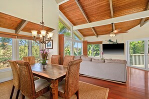 A spacious dining area with a wooden table, wicker chairs, and a chandelier. - 3 bedrooms with baths, air conditioning and heated pool near Grand Hyatt. (Koloa)