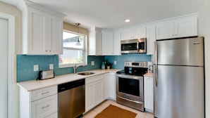 A modern kitchen with white cabinets, stainless steel appliances, a microwave, oven, and dishwasher. - Anna Cabana B: Pool Home, AMI North End, 2 Blocks to Beach by Anna Maria Life Vacation Rentals (Anna Maria)