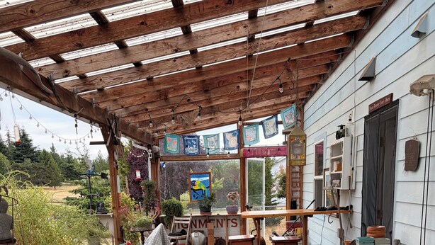 Une terrasse couverte, aménagée avec des meubles en bois, une table et divers objets.