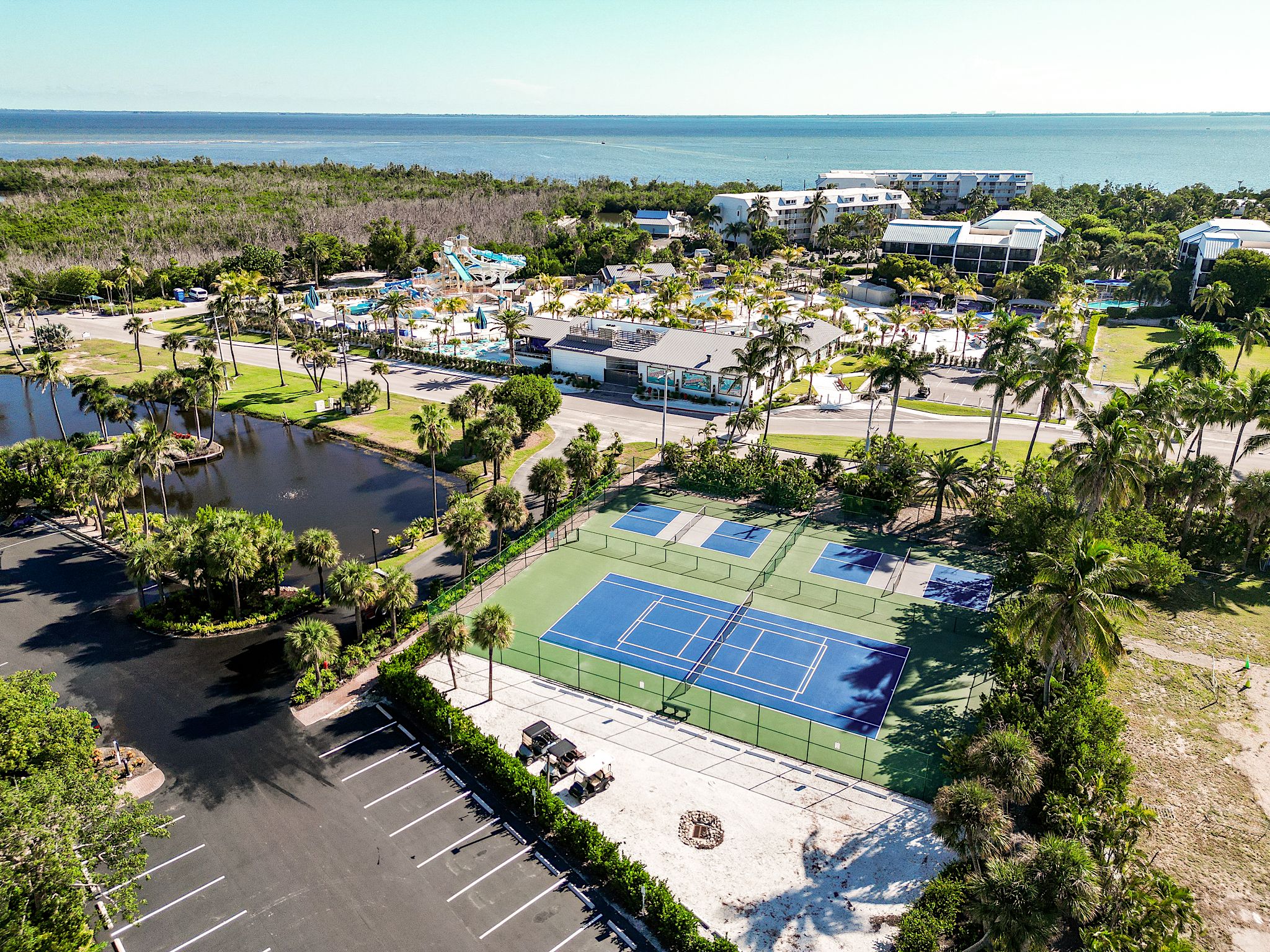 A resort with a tennis court, pool, and beachfront view.