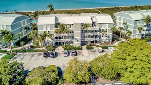 A resort with multiple buildings, a parking lot, and a view of the ocean. - Stunning Modern beach front unit - completely renovated!  Includes golf cart! (Captiva)