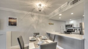 A modern kitchen with white cabinets, a stainless steel refrigerator, and a microwave. - Stunning Modern beach front unit - completely renovated!  Includes golf cart! (Captiva)