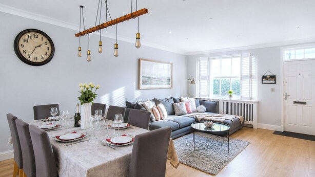A dining area with a table set for four, a sofa, and a window with blinds. - Spacious quiet 4BR/6beds house with private garage (London)