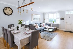 A dining area with a table set for four, a sofa, and a window with blinds.