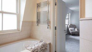 A bathroom with a bathtub, a towel rack, and a door leading to another room. - Spacious quiet 4BR/6beds house with private garage (London)