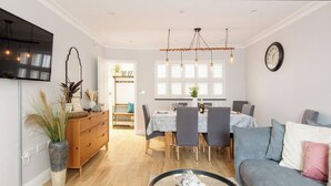 A modern living room with a sofa, a coffee table, and a dining area with a table and chairs. - Spacious quiet 4BR/6beds house with private garage (London)