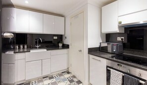 A modern kitchen with white cabinets, a black countertop, and a microwave.