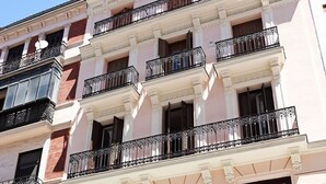Un edificio de varios pisos con un estilo arquitectónico clásico, que presenta balcones con barandales ornamentados y grandes ventanales.