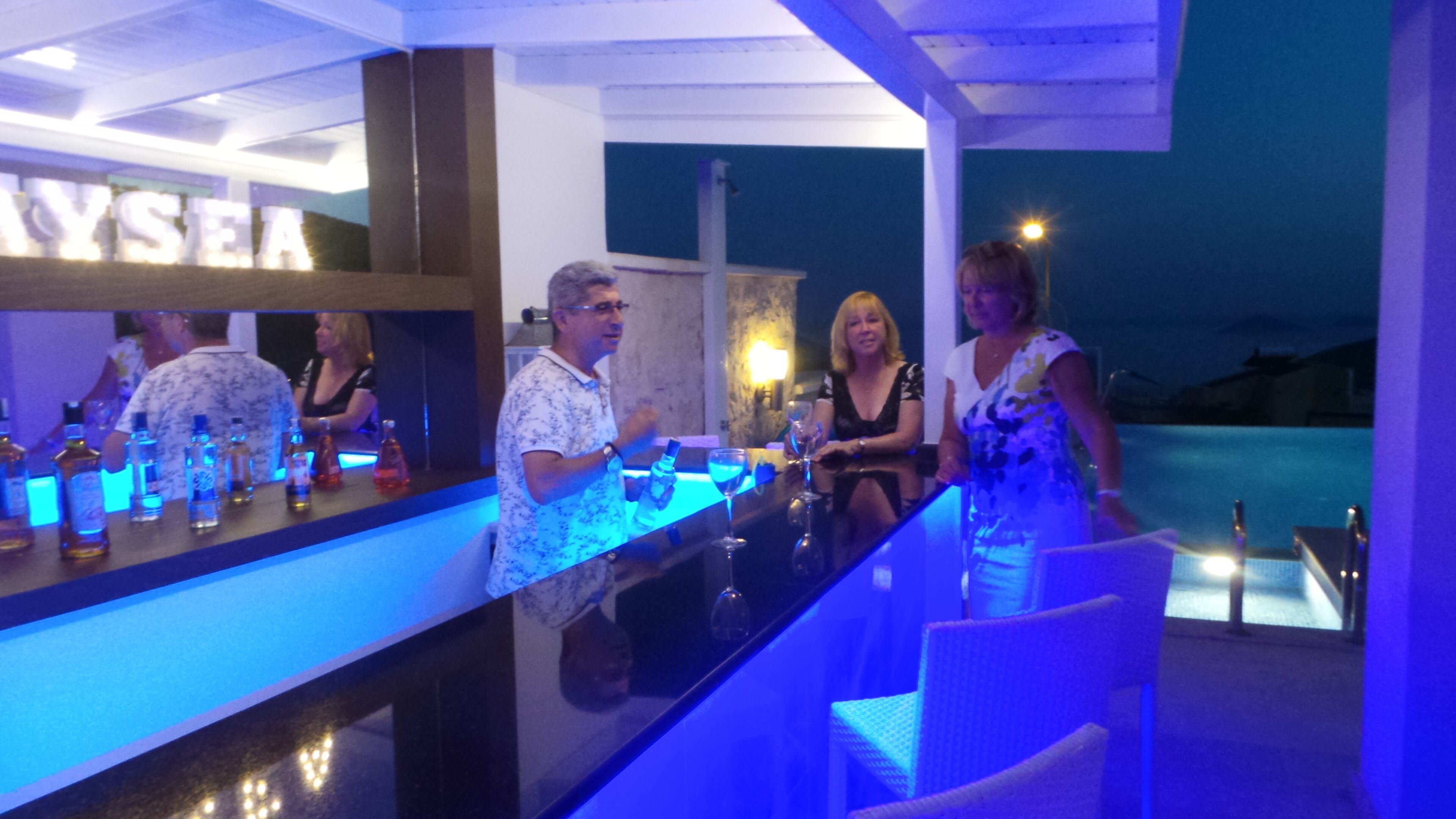 Zona de bar con vista a la piscina, barra y asientos.