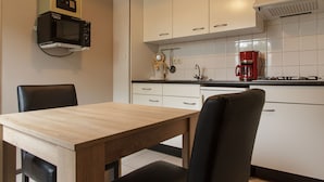 Una cocina moderna con armarios blancos, una mesa de comedor de madera y sillas negras.