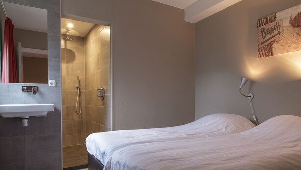 Un baño moderno con ducha, lavamanos y cama.
