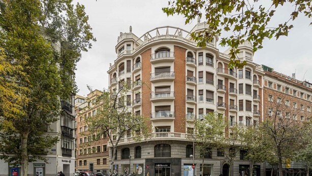 A multi-story building with a curved facade, multiple balconies, and a ground-level entrance.