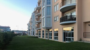 Un moderno edificio de apartamentos con varios balcones, ventanas amplias y un césped bien cuidado.