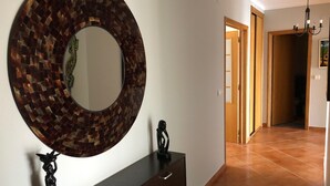 Un pasillo con un espejo redondo, un aparador de madera oscura y suelo de baldosas.