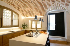 Una cuina moderna amb una illa gran, il·luminació penjant i vista a la ciutat per la finestra.