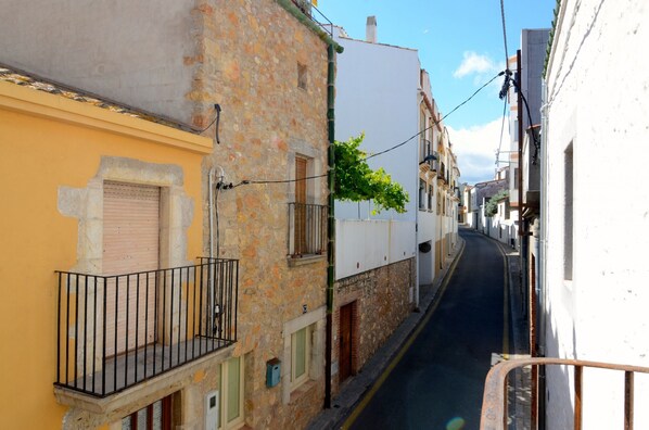 A narrow street with buildings on either side, featuring balconies and a clear sky. - CASA ROSA DEL PORT (L'Escala)