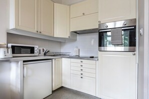 A modern kitchen with white cabinets, stainless steel appliances, and a microwave.