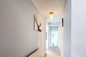 A hallway with a radiator, a wall-mounted deer head decoration, and a chandelier.