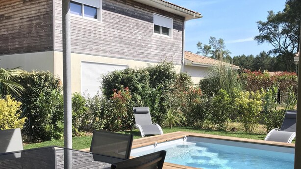 Un espacio al aire libre cubierto con piscina, terraza de madera y una mesa con sillas.