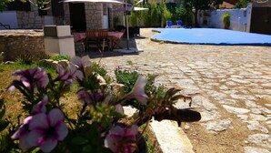 A stone patio with a pool area, outdoor furniture, and flowering plants. - Louro's Villa in Vila Nova (Coimbra)