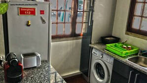 A compact kitchen with a washing machine, a toaster, and a green dish rack. - Louro's Villa in Vila Nova (Coimbra)