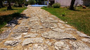 A stone pathway leading to a building with a blue roof.