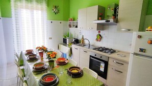 A kitchen with a dining table set for four, a microwave, stove, and refrigerator.
