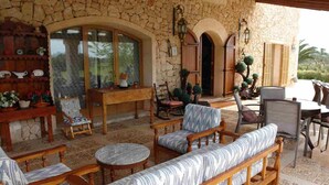 A stone-walled patio with outdoor seating, including wooden benches and chairs, and a table. - Villa 18 pax with large pool close to Es Trenc (Campos - Sa Rapita)