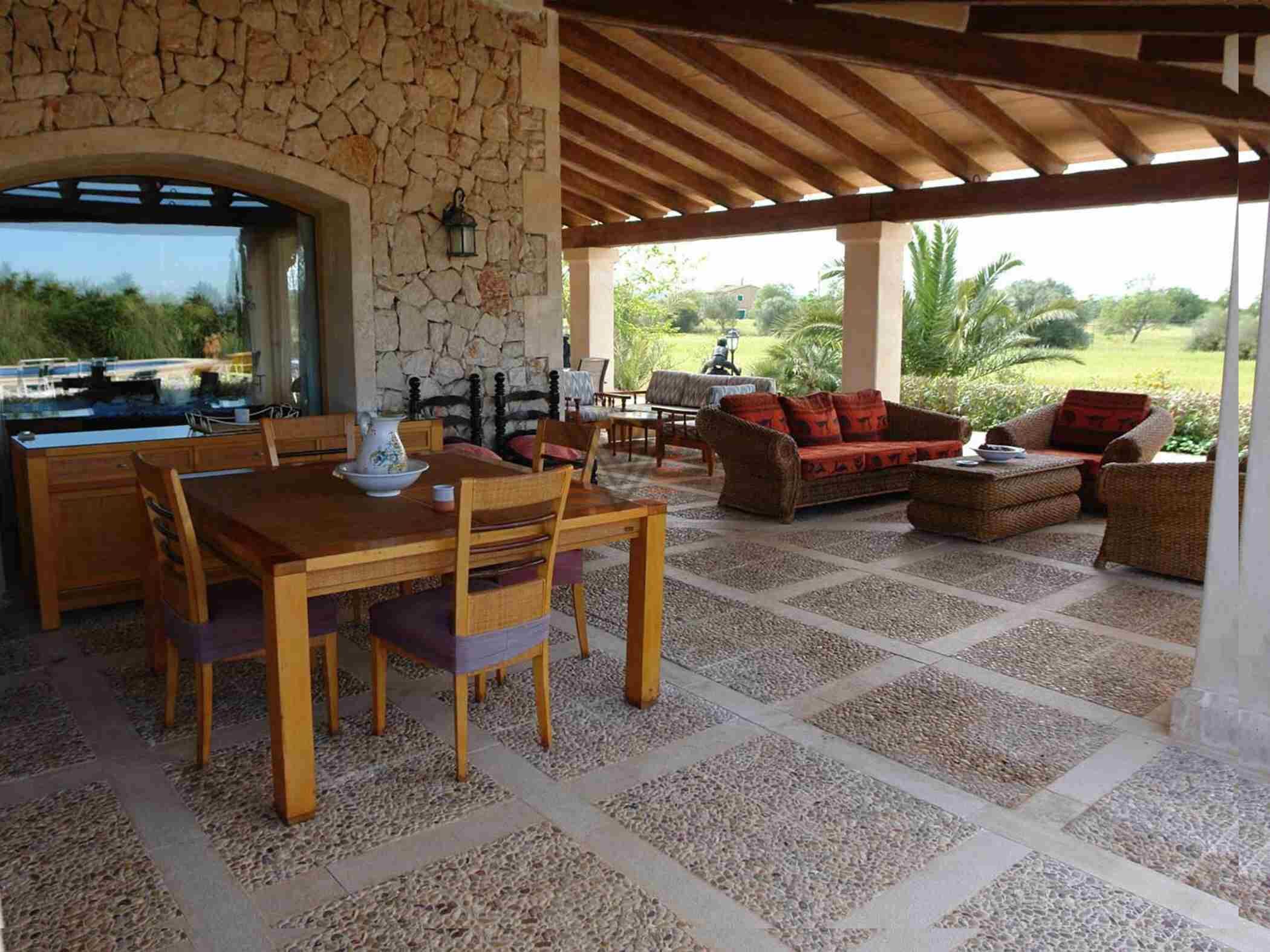 An outdoor patio area with a stone wall, wooden furniture, and a view of the surrounding landscape.