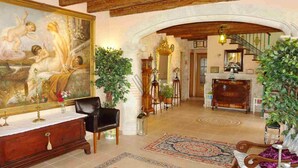 A grand lobby with a large classical painting, a wooden bench, a red rug, and a decorative fireplace. - Villa 18 pax with large pool close to Es Trenc (Campos - Sa Rapita)