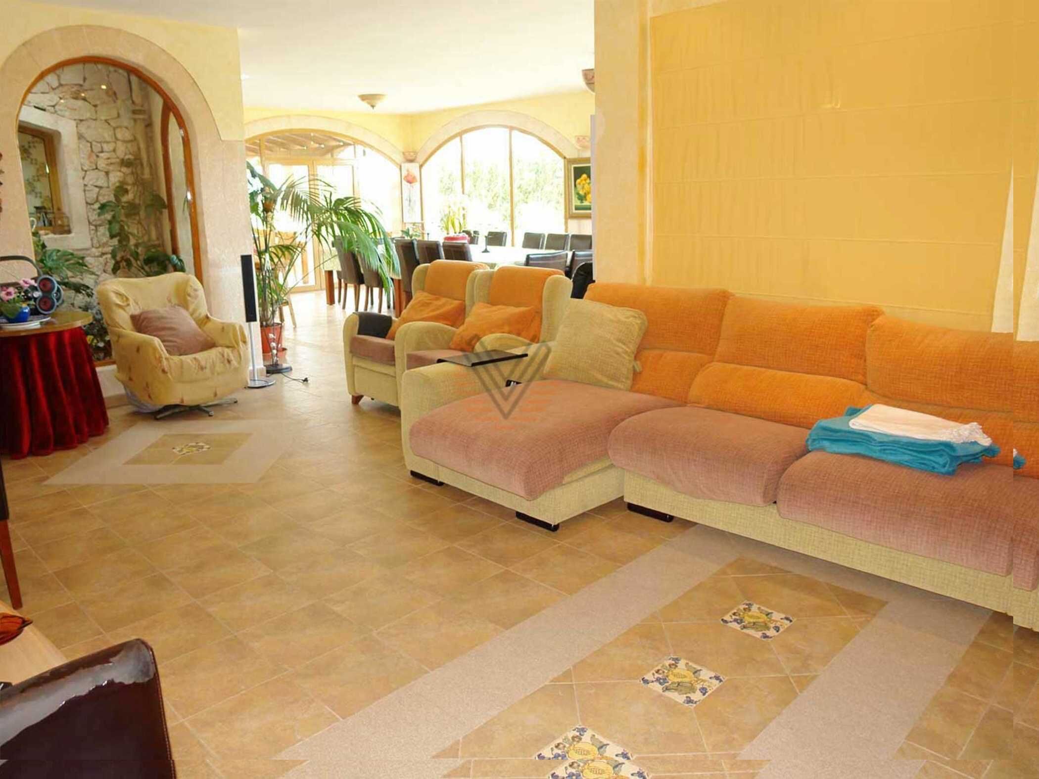 A spacious living area with a beige sofa, a yellow armchair, and a red table with a potted plant.