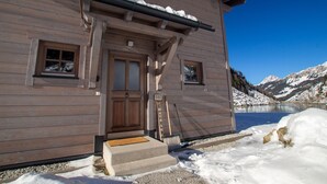 A wooden chalet with a wooden door, windows, and a number sign '162' outside.