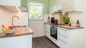 A modern kitchen with a wooden countertop, white cabinets, and a built-in oven. - Frida - Family vacation home, WLAN free, sauna, fireplace, 8 persons (Fehmarn)