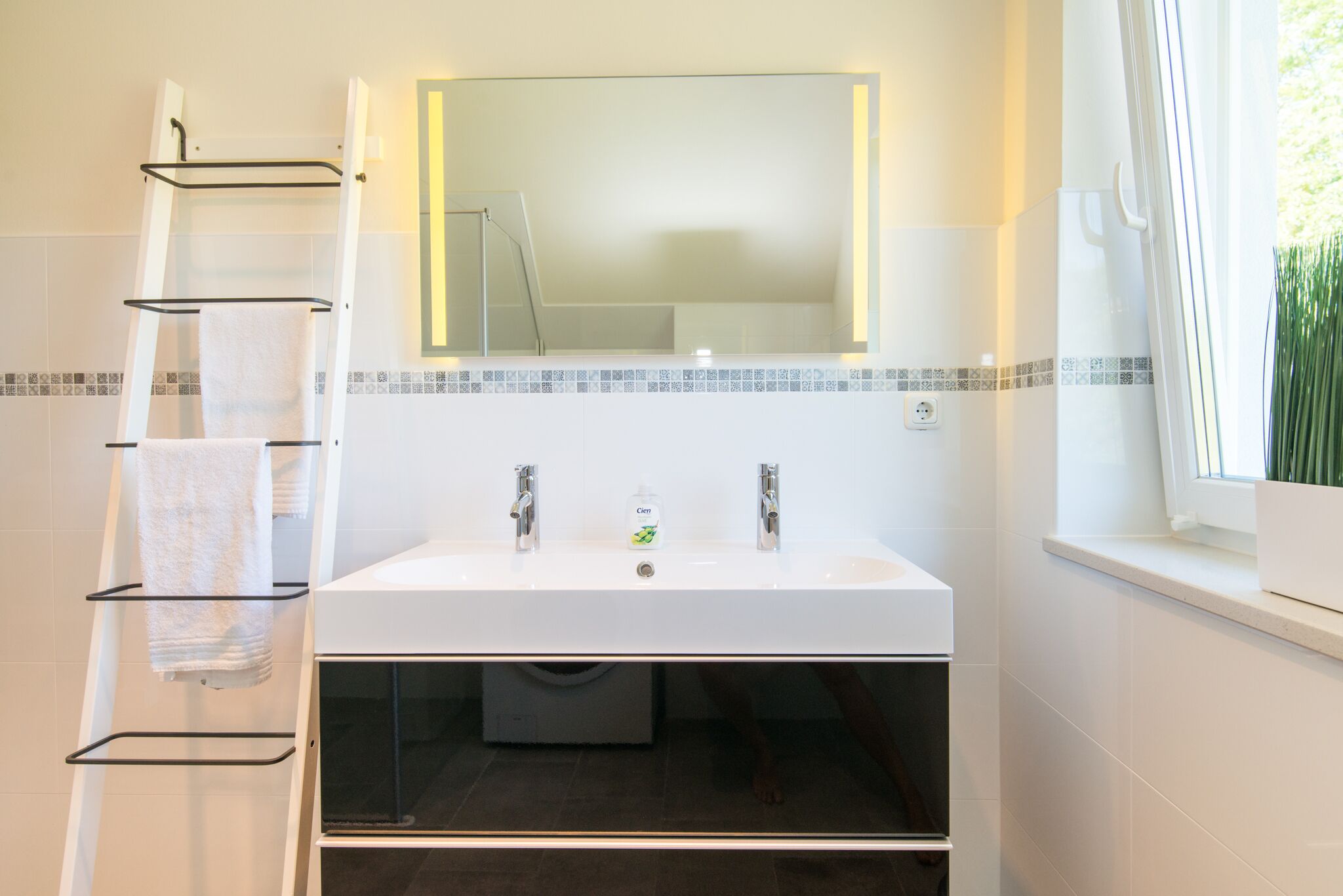 A bathroom with a white sink, two faucets, a mirror, and a towel rack.
