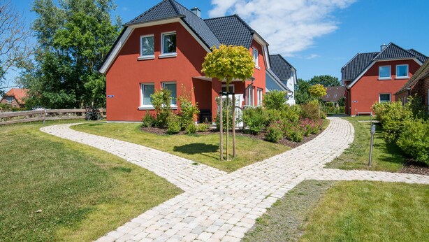 A red house with a paved driveway and a tree in front. - Frida - Family vacation home, WLAN free, sauna, fireplace, 8 persons (Fehmarn)