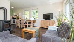 A modern living room with a grey sofa, a wooden coffee table, and a TV in the background. - Frida - Family vacation home, WLAN free, sauna, fireplace, 8 persons (Fehmarn)