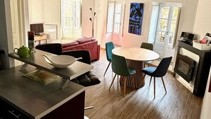 Una cuina moderna amb sostre de fusta, una zona de menjador amb taula rodona i cadires, i un espai d'estar acollidor amb un sofà vermell.