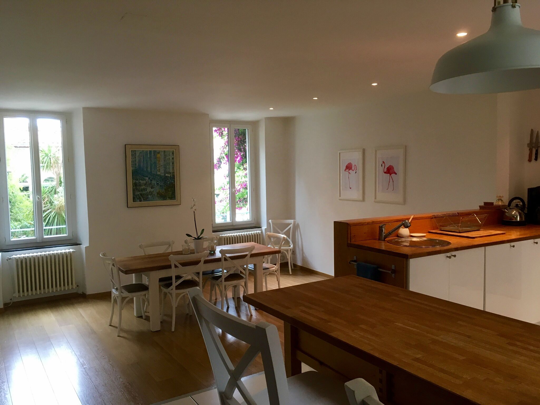 Une cuisine moderne avec une table et des chaises en bois, un four encastré et une fenêtre donnant sur un paysage verdoyant.