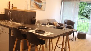 A modern kitchen with a central island, bar stools, and a dining area with a sofa and chairs. - Little parenthesis in Trinité-Sur-Mer (La Trinité-sur-Mer)