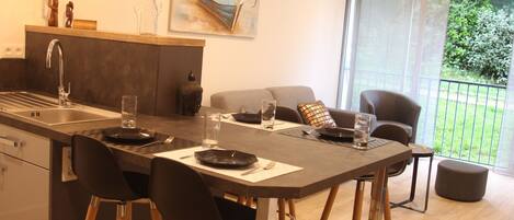 A modern kitchen with a central island, bar stools, and a dining area with a sofa and chairs.