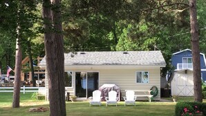 A small house with a covered patio, a fenced yard, and a garage. - Home on the lake. Walk out your door for Swimming, boating or morning coffee. (Mears)