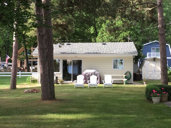 A small house with a covered patio, a fenced yard, and a garage.