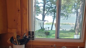 A kitchen with a granite countertop, a white sink, wooden cabinets, and a window overlooking a lake. - Home on the lake. Walk out your door for Swimming, boating or morning coffee. (Mears)