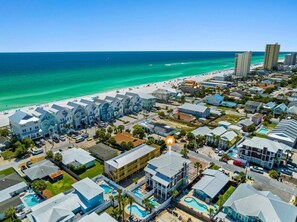 A coastal residential area with beachfront properties, a swimming pool, and a clear view of the ocean.