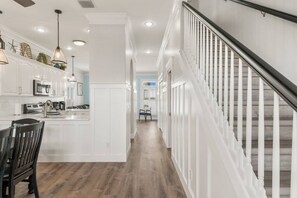 A modern kitchen with white cabinetry, a central island, and a dining area with chairs.