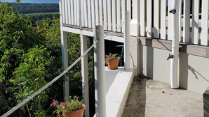 A balcony with a white picket fence, potted plants, and a view of the landscape.